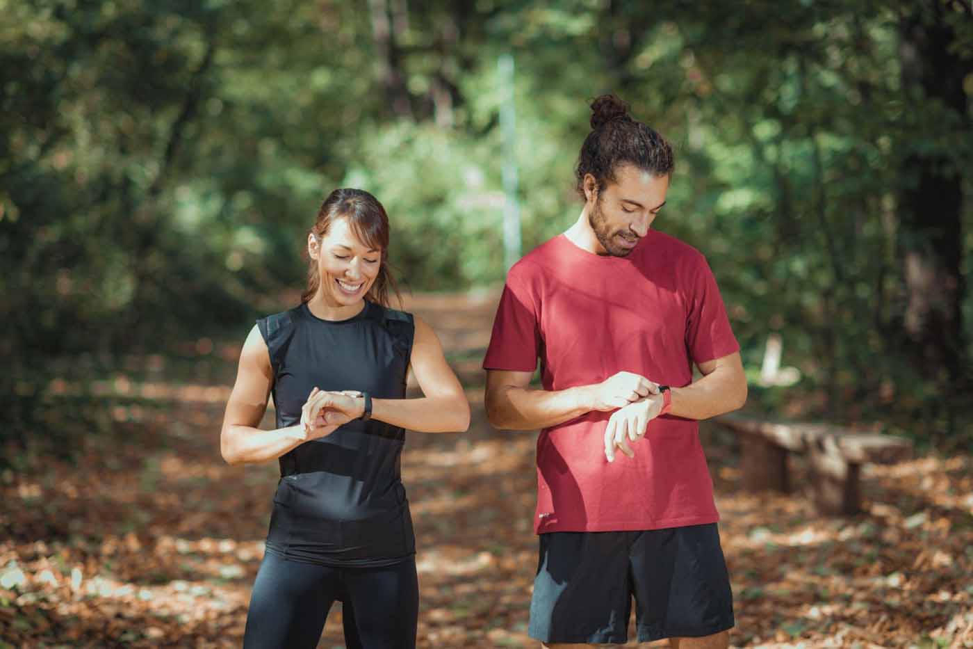 Young couple looking at their smart watches after outdoor training