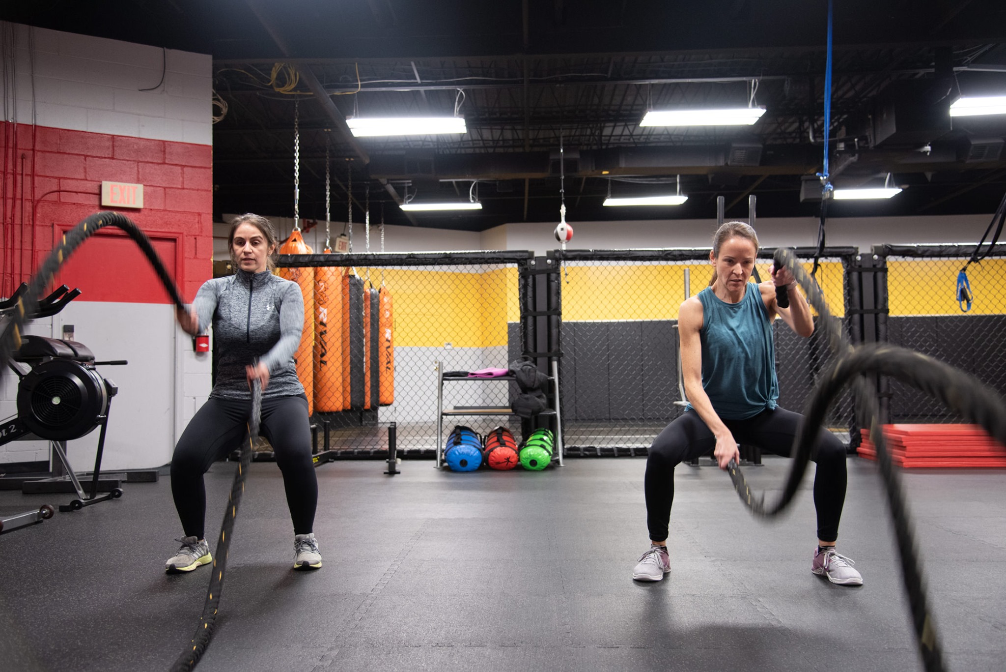 Two women doing a battle ropes workout in a small group fitness class at PFMA