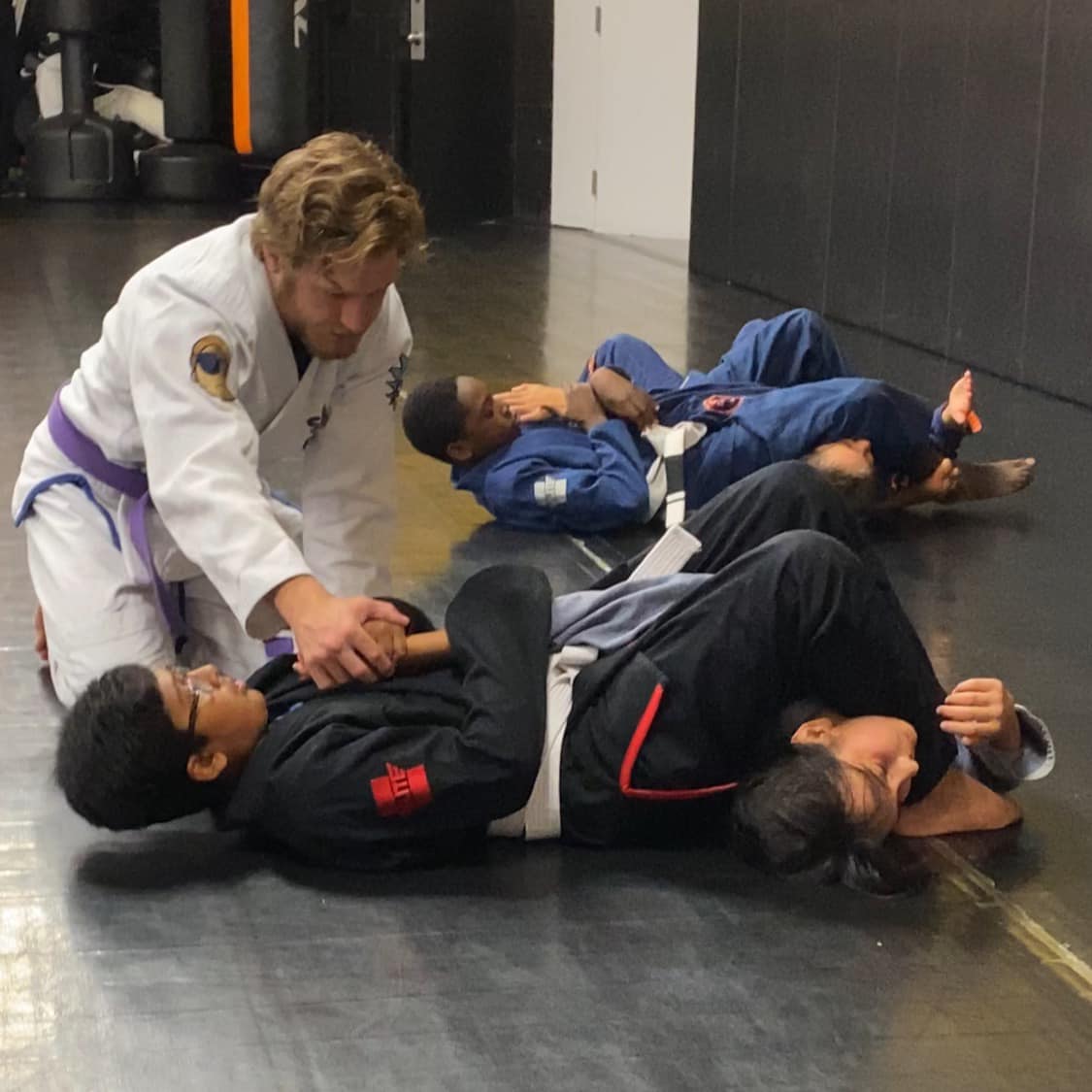 Coach teaching proper arm bar technique to the kids.