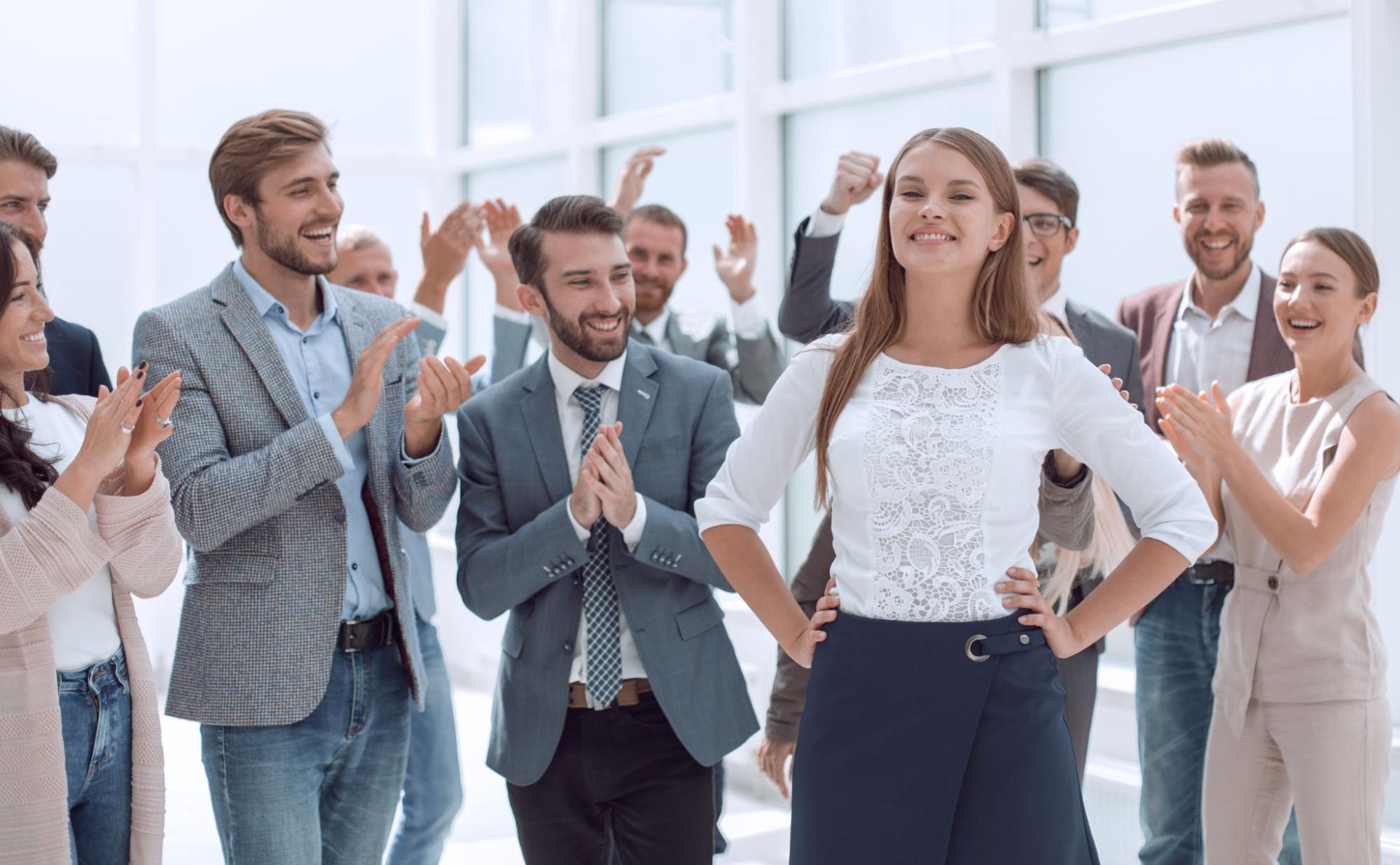 Business team cheering for a successful, confident female colleague at work