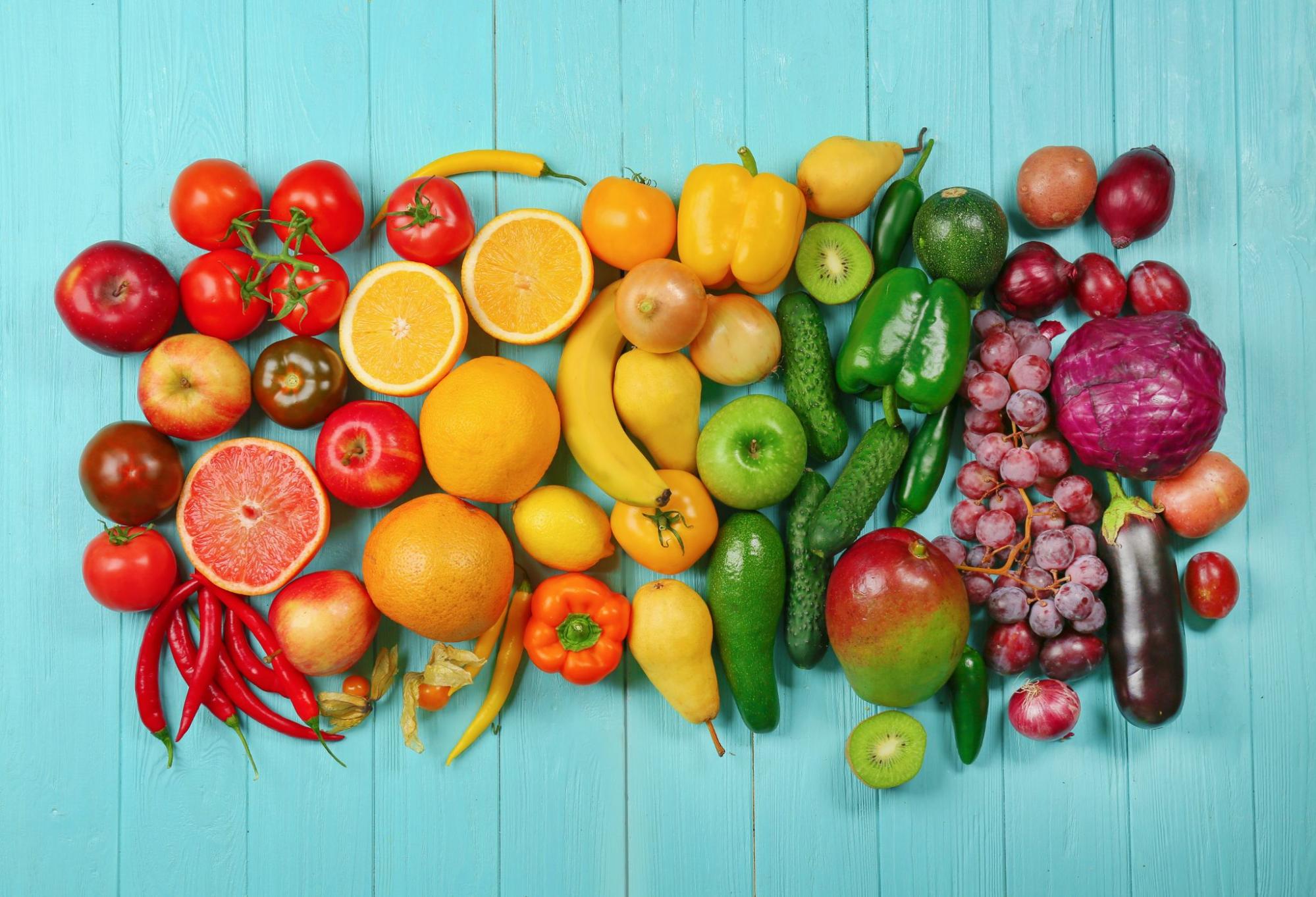 Creative composition made of fruits and vegetables in rainbow colors on wooden background
