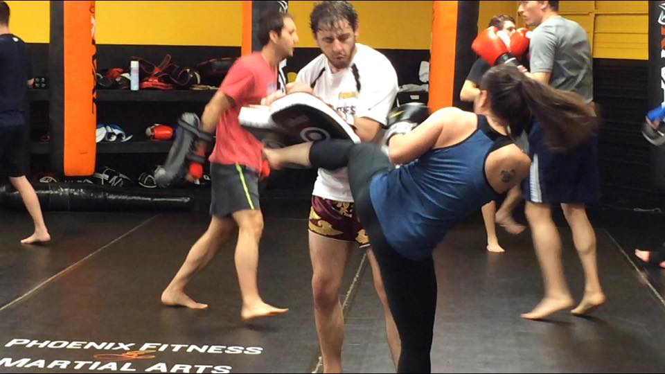 Woman kicking pads during kickboxing workout at Phoenix Fitness and Martial arts
