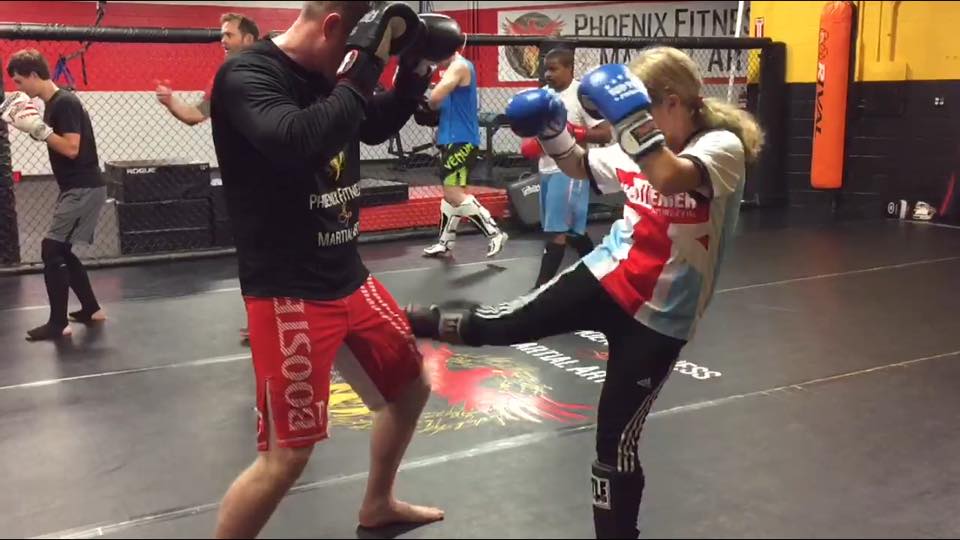 Woman kicking man during kickboxing workout at Phoenix Fitness and Martial arts