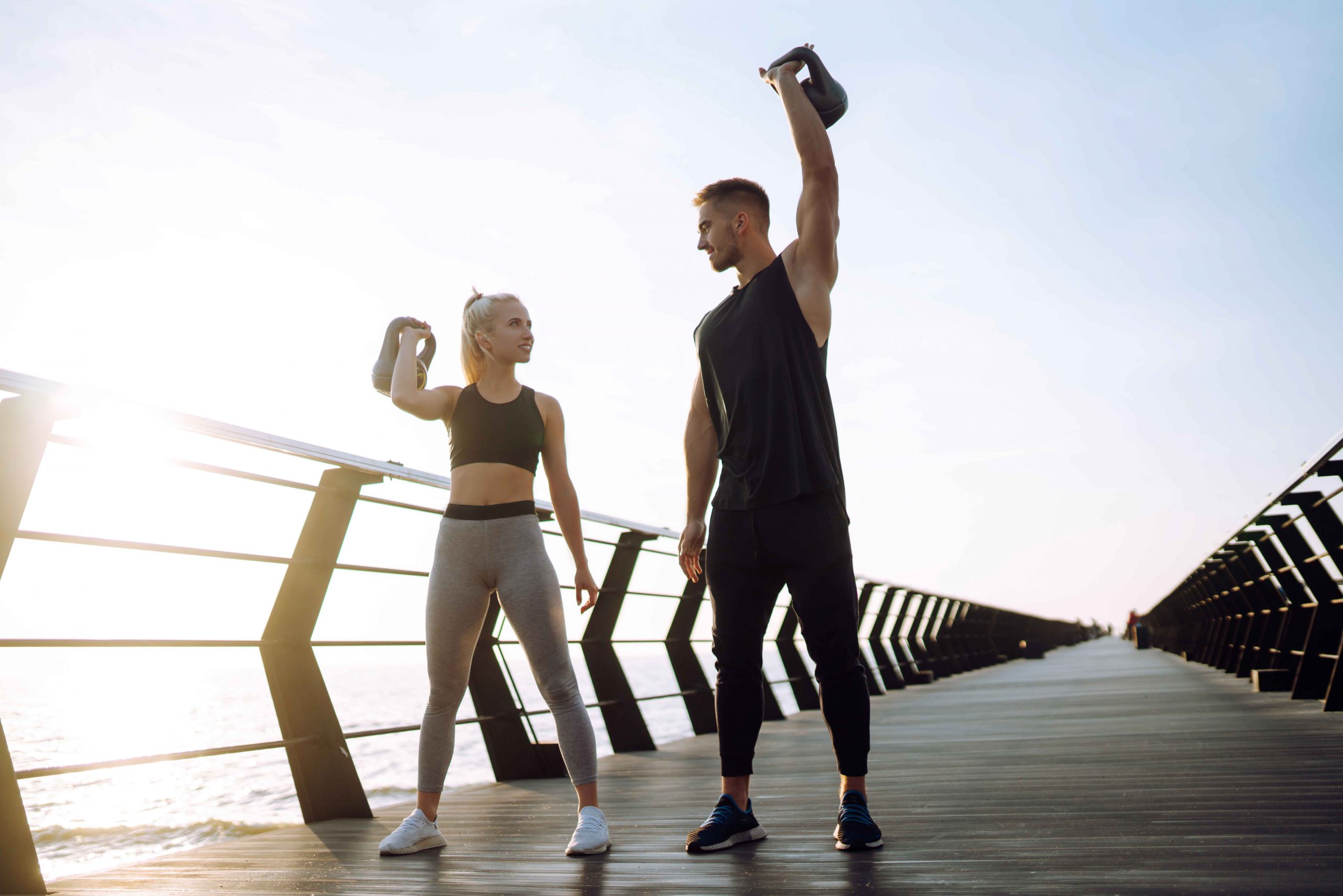 Couple works out on at the beach with kettlebells