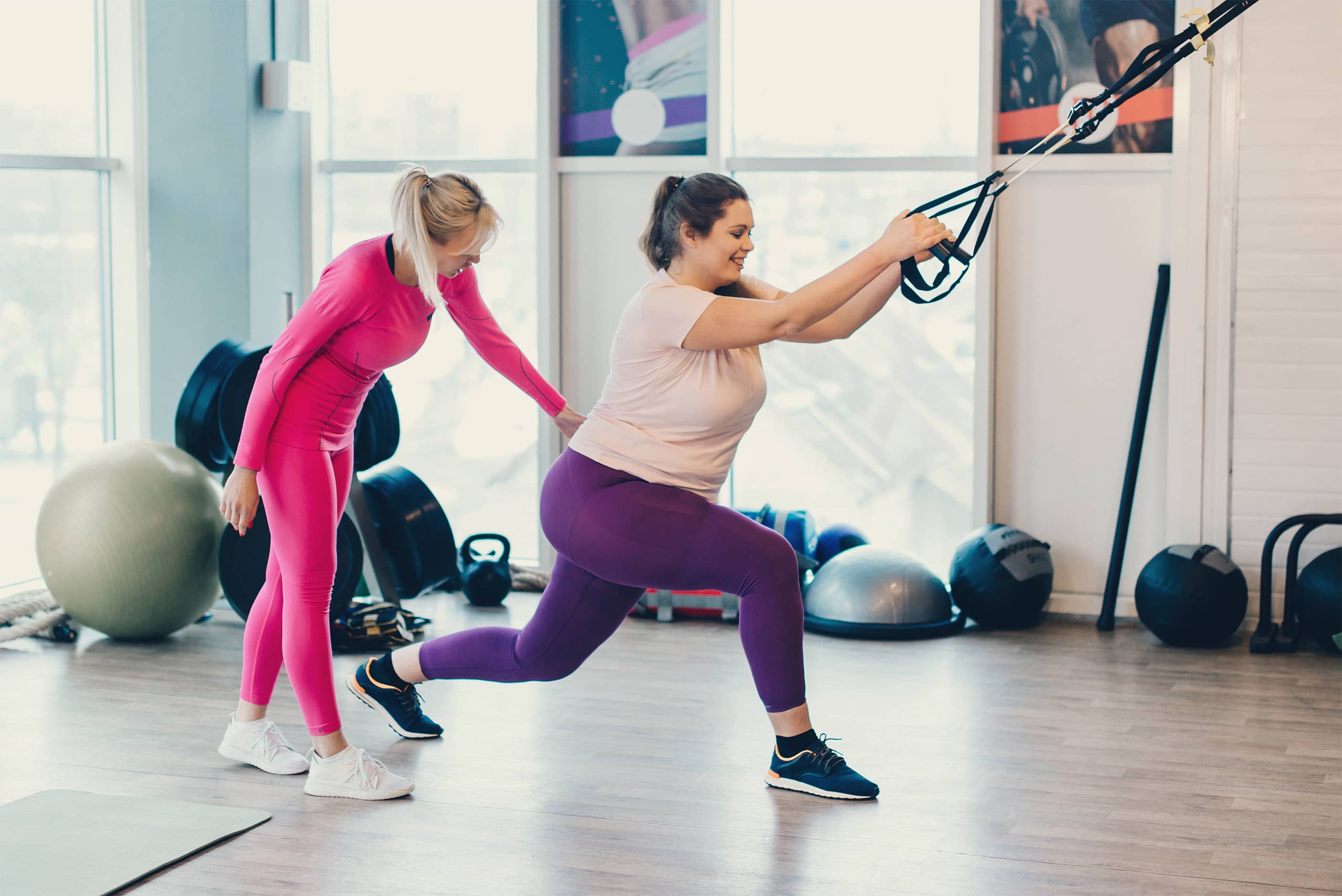 Female personal training assisting woman stretching