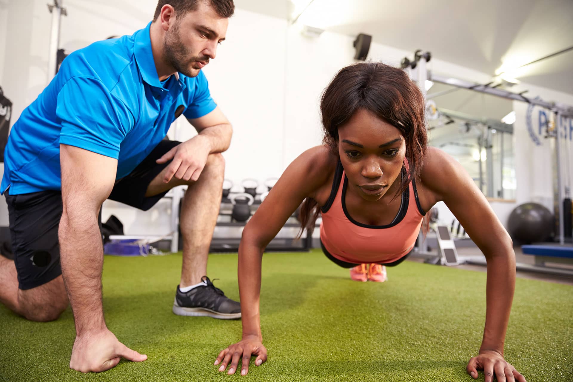 Male trainer helping a woman do pushups